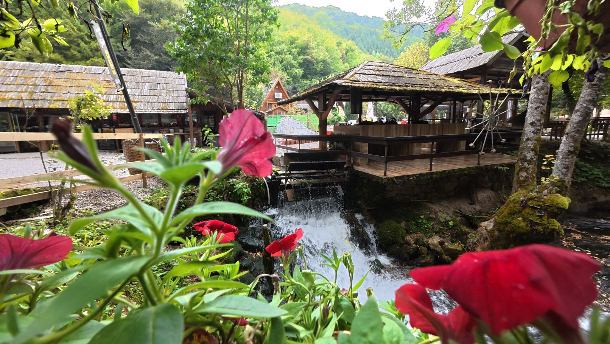 Wooden bridge and small waterfall in Semešnica near Donji Vakuf, surrounded by flowers and greenery